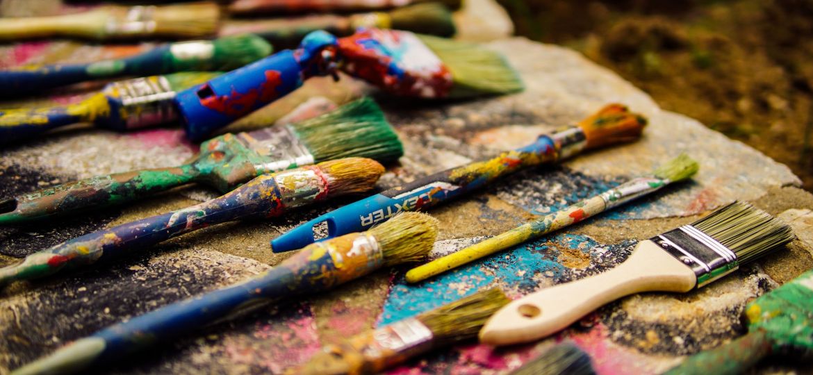 A photograph of several paintbrushes of different sizes covered in dried paint.