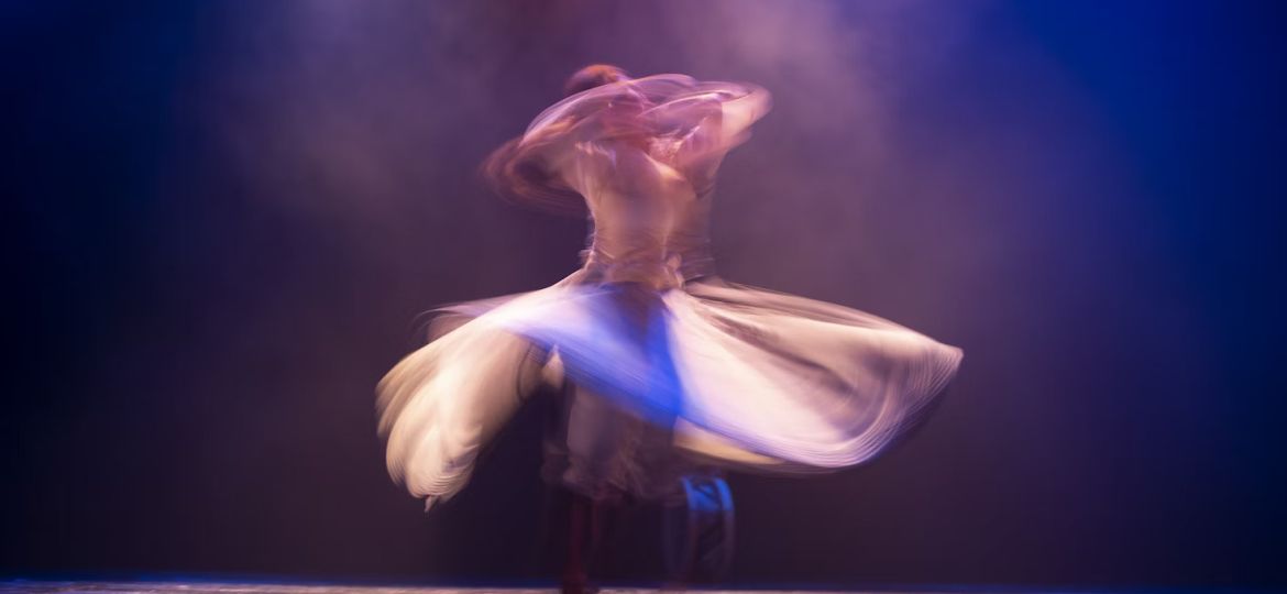A blurred image of a woman in white long sleeve shirt with white scarf from a solo dance in a live show during Ramallah Contemporary Dance Festival.