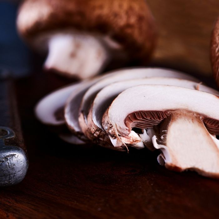 Sliced white and brown mushrooms on brown wooden table.