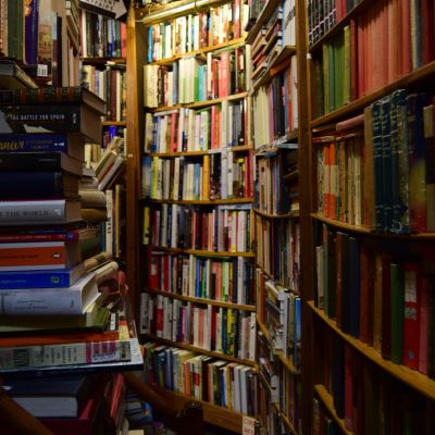 A dimly lit bookshelf corner with books stacked haphazardly