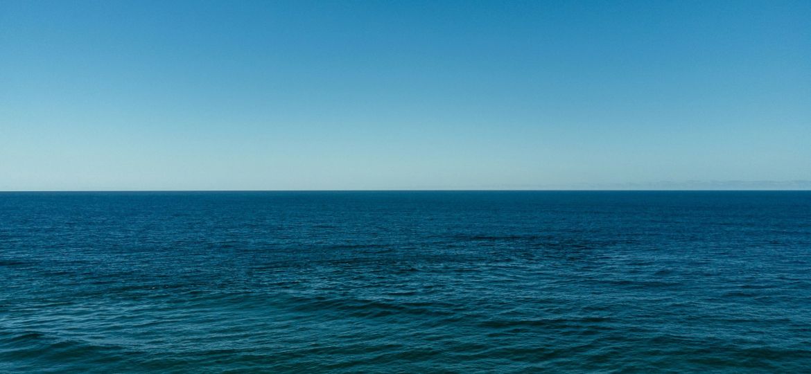 A photograph of the blue sea and the horizon in the distant.