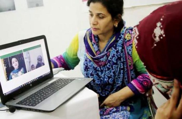 Two women are consulting a female doctor via web calls on a laptop.