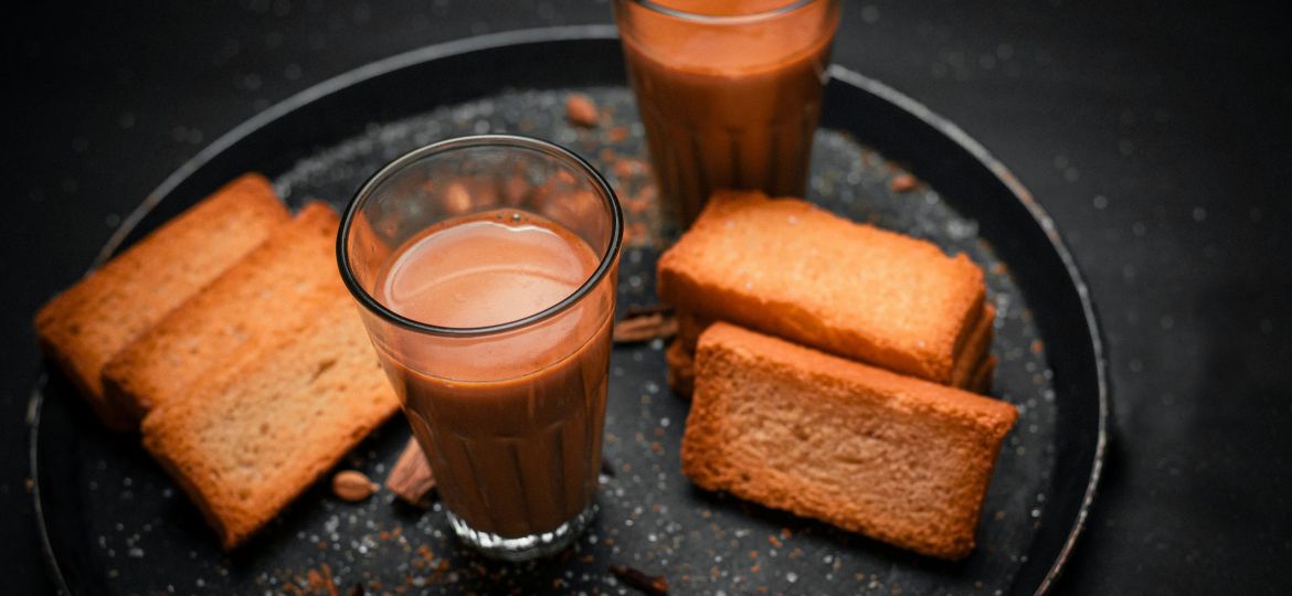 Two glasses of chai with rusk/dry biscuits to share