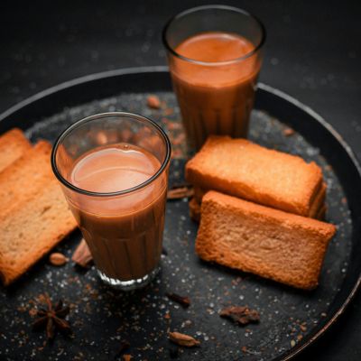 Two glasses of chai with rusk/dry biscuits to share