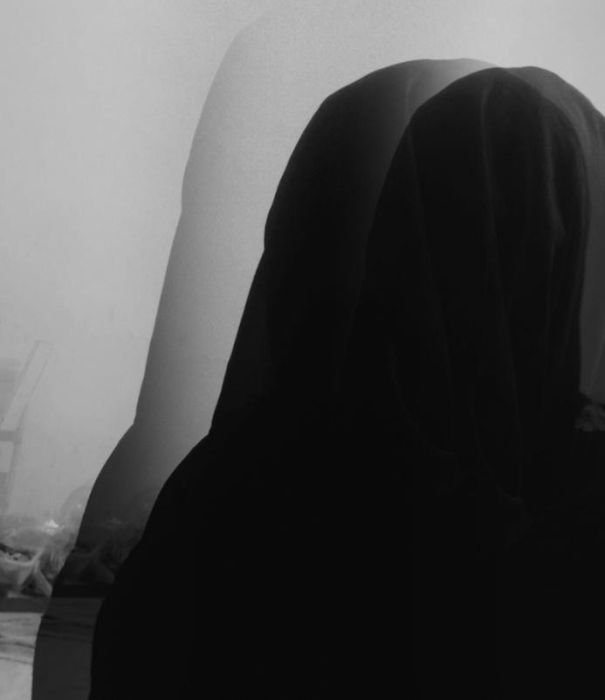 A vignette of a woman covering her head from behind