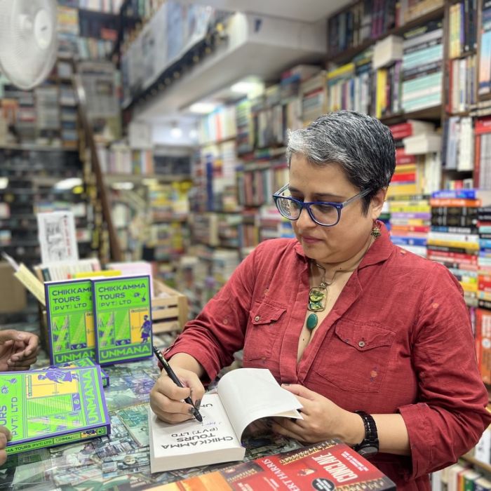 Unmana signing a copy Chikkamma Tours (Pvt.) Ltd in a bookshop