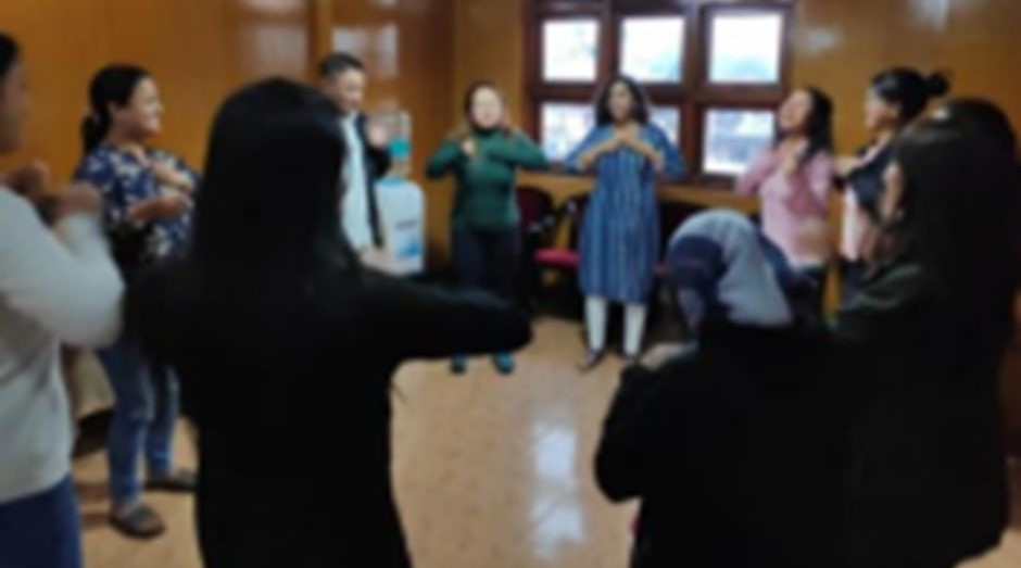 Untitled design - 1 A group of trainers standing in a circle and participating in an exercise